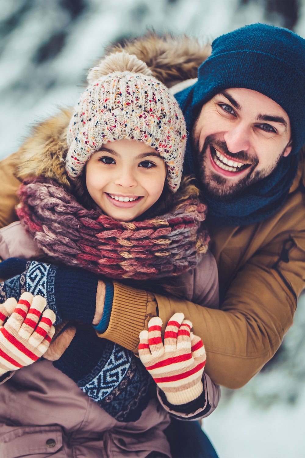 Handsome young dad and his little cute daughter are having fun outdoor in winter. Enjoying spending time together.